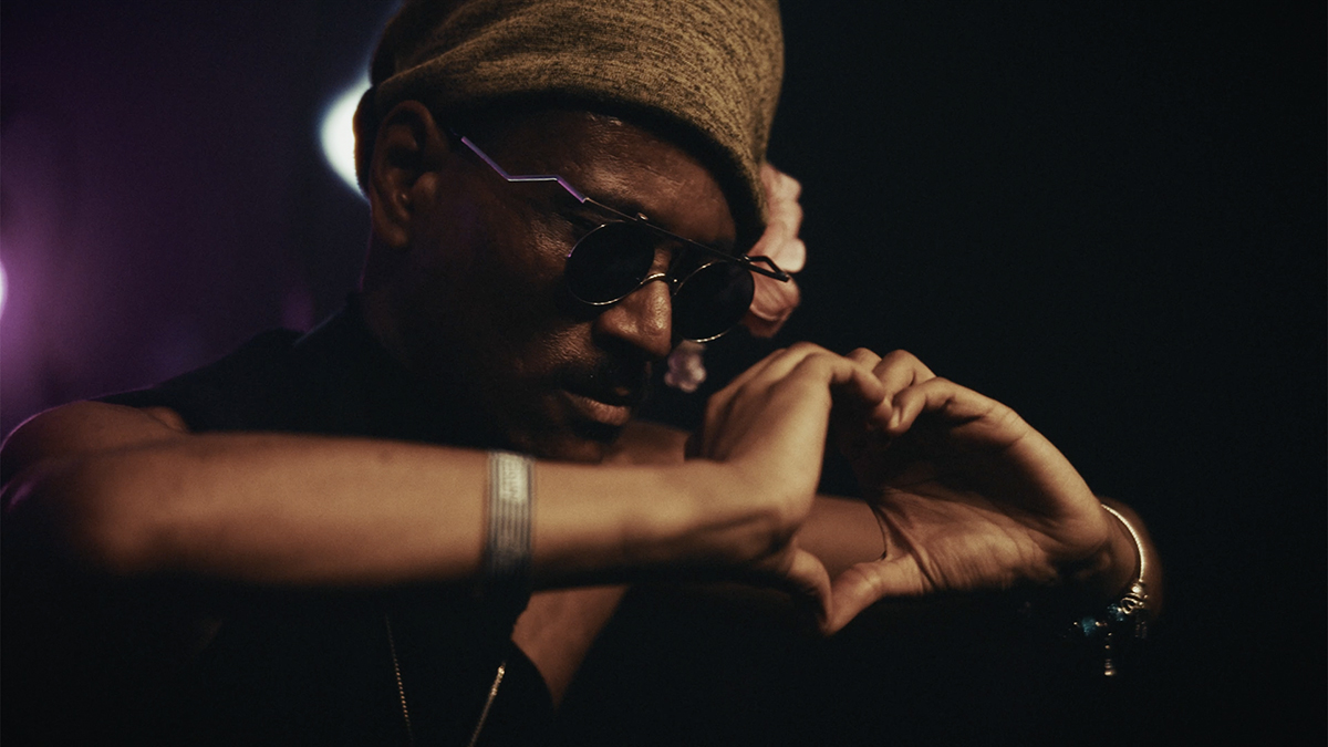 Tomoki Sanders on stage at Le Guess Who, holding his hands out to the audience in a heart shape